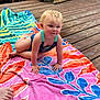 Vivian is registered to the contest to win money with this photo: toddler, child, crawling, beach_towel, colorful, wooden_deck, outdoor, summer, wet_hair, blonde_hair, curious, sunlight, natural_light, casual, relaxed, playful, skin, person, baby, deck_railings
