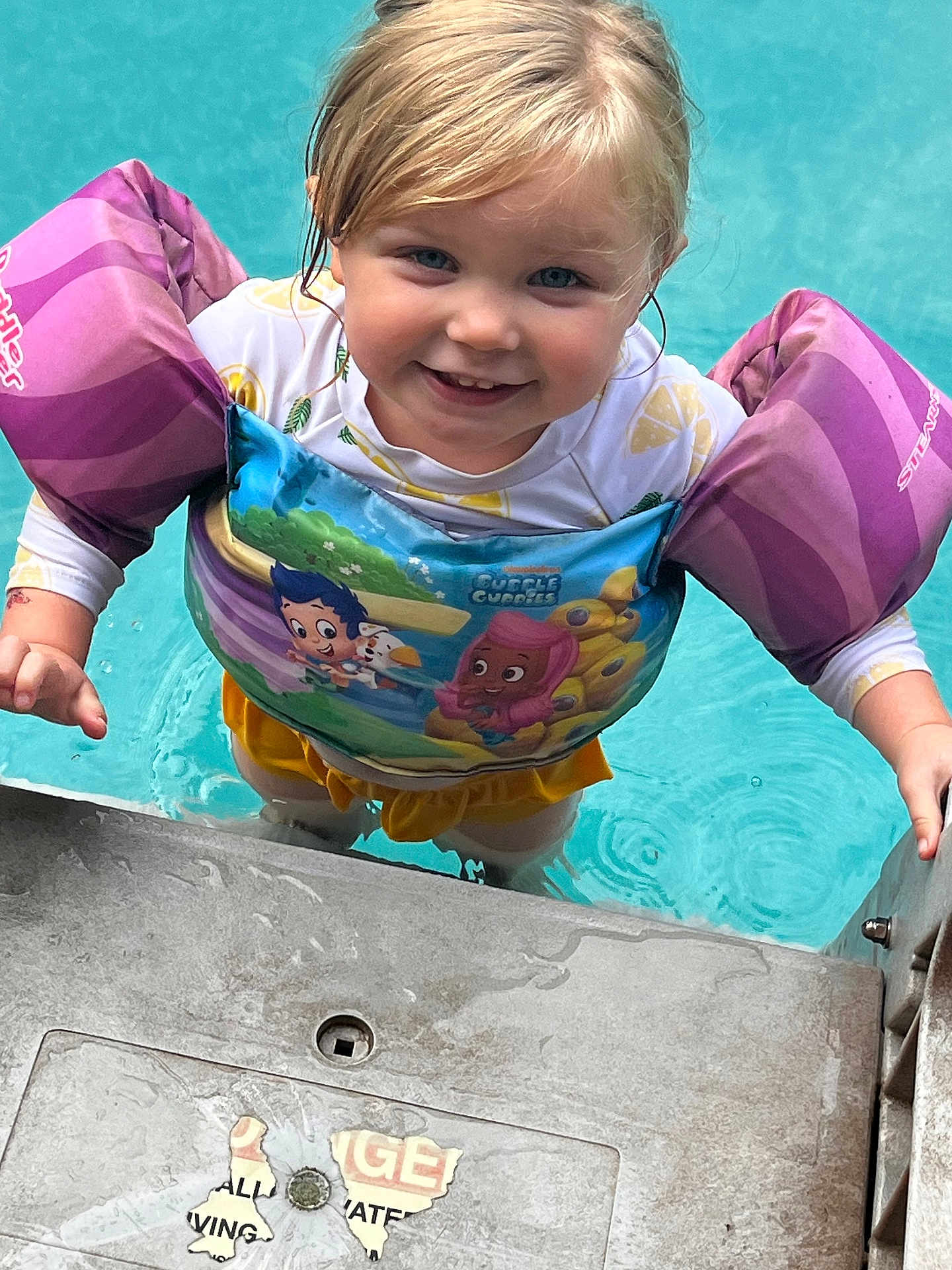 Vivian joined the competition — help win amazing prizes! child, toddler, pool, water, floaties, life_jacket, swimwear, smiling, outdoor, summer, concrete, climbing, happy, blue_eyes, blonde_hair, splash, safety, fun, water_play, cute