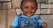 Jeremiah is registered to the contest to win money with this photo: toddler, child, baby, smiling, denim_overalls, blue_shirt, stone_wall, concrete, barefoot, cute, happy, portrait, outdoor, sitting, young_child, person, infant, casual_clothing, expression, joyful