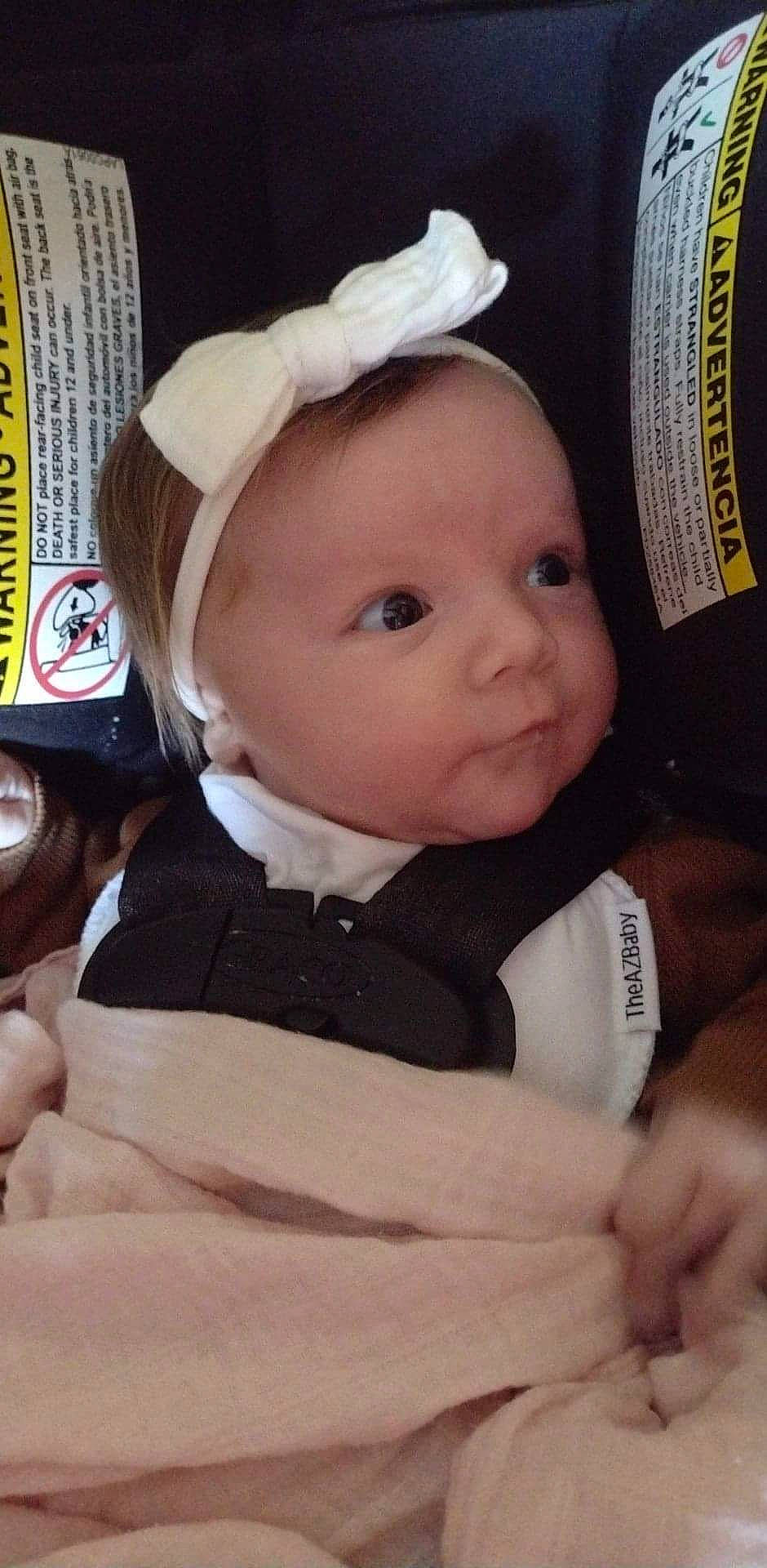 Melanie is registered to the contest to win money with this photo: baby, baby_products, baby_toddler_clothing, cap, cheek, child, comfort, costume_hat, eye, eyebrow, fashion_accessory, fur, happy, hat, iris, person, room, sitting, sleeve, toddler