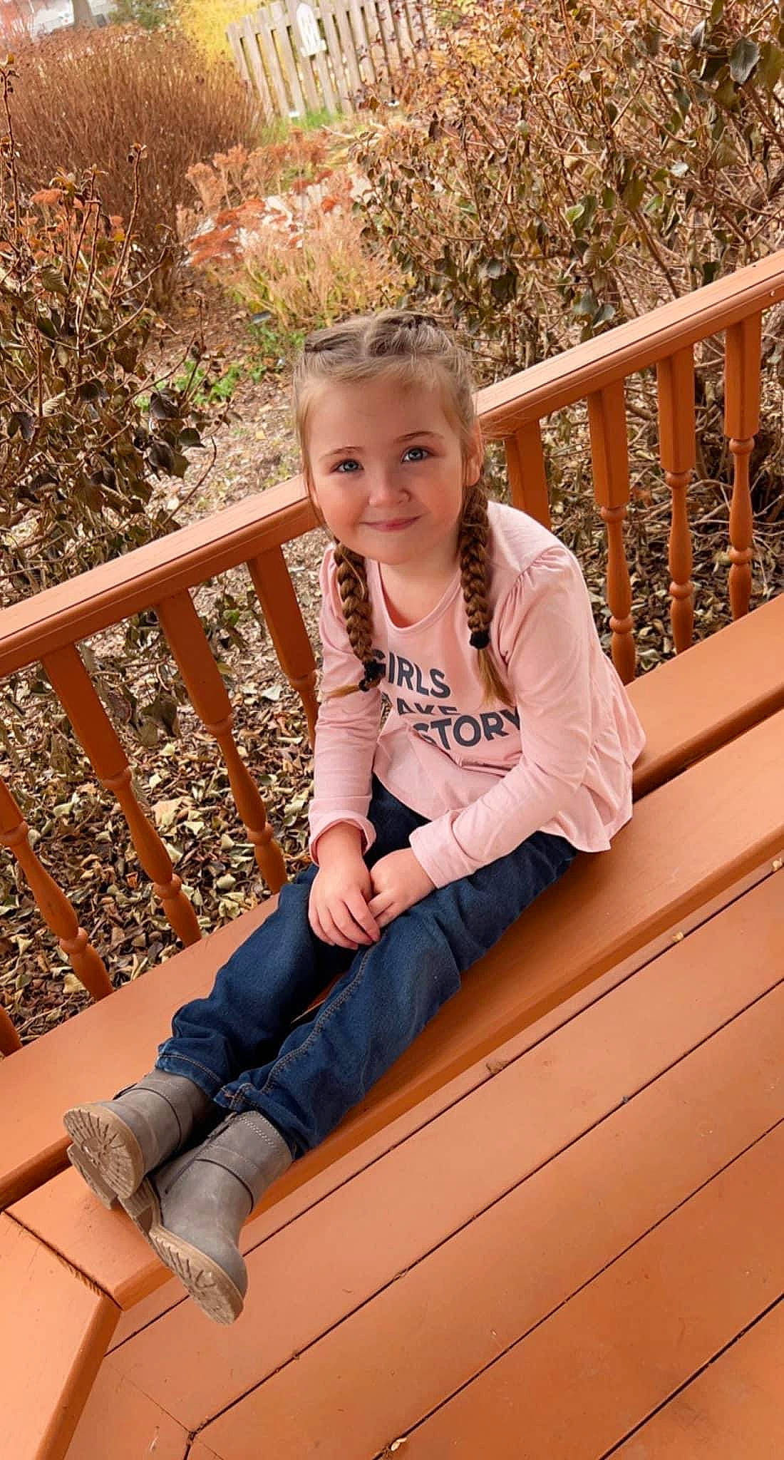 Annabelle is registered to the contest to win money with this photo: blond, child, facial_expression, fawn, fence, fun, grass, happy, hardwood, human_leg, joy, knee, leg, leisure, long_hair, person, plant, smile, t_shirt, thigh