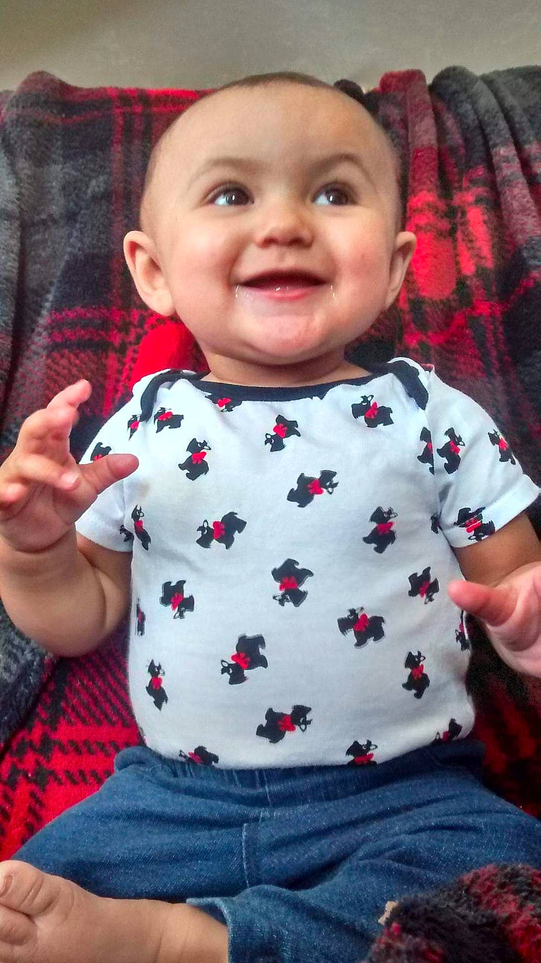 Arianna is registered to the contest to win money with this photo: baby, baby_toddler_clothing, cheek, chin, clothing, collar, face, facial_expression, finger, gesture, joy, organ, person, product, skin, sleeve, smile, standing, t_shirt, tartan