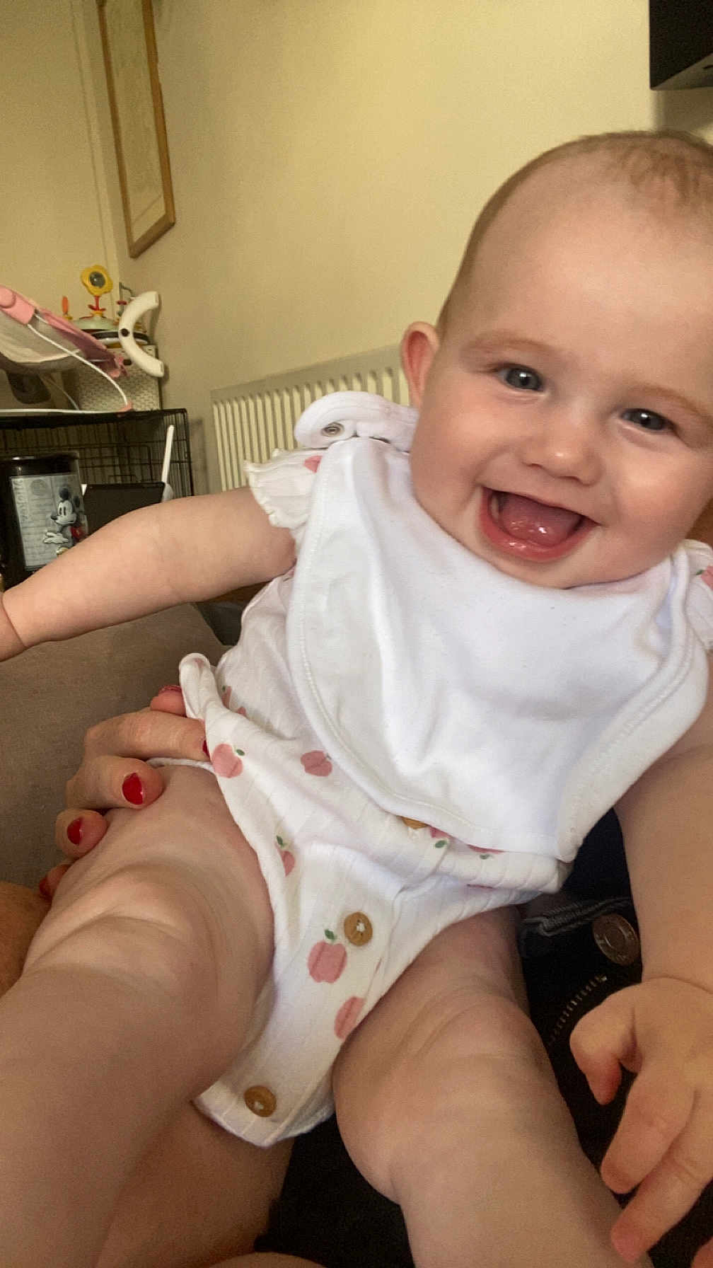 Theia joined the competition — help win amazing prizes! baby, smiling, infant, happy, white_clothing, bib, person, indoor, skin, hand, legs, face, holding, furniture, background, radiator, toy, can, red_nail_polish, closeup