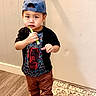 Thawng joined the competition — help win amazing prizes! toddler, child, barefoot, indoor, car_design, cap, blue_cap, black_tshirt, brown_pants, toothbrush, curious, standing, rug, door, wall, wood_floor, person, young_child, casual_clothing, home