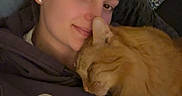 Pumpkin joined the competition — help win amazing prizes! woman, cat, orange_cat, snuggling, indoor, pillow, patterned_pillow, cozy, relaxed, casual_clothing, hoodie, earrings, portrait, pet, affection, resting, home, cute, friendship, comfort