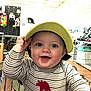 Ryan is registered to the contest to win money with this photo: baby, child, shopping_cart, visor, striped_shirt, dinosaur_patch, smile, blue_eyes, hand, store, shopping, aisle, boxes, shelves, indoor, happy, person, clothing, infant, cute