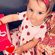 Gioia participe au concours pour gagner de l'argent avec cette photo : child, colorful, curious_eyes, cute, dress, fabric, girl, hair_clip, heart_emoji, holding, indoor, patterned_clothing, person, portrait, red_box, sitting, smiling, strawberry, toddler, young_child