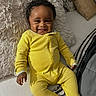 baby, child, infant, smiling, happy, portrait, bed, bedding, pillow, blanket, yellow_onesie, clothing, indoor, bedroom, lying_down, curly_hair, face, hands, cozy, photograph