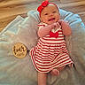 baby, infant, four_months, smiling, happy, portrait, headband, red_dress, striped_clothing, bow, blanket, lying_down, indoor, wooden_floor, milestone, four_months_sign, face, hands, feet, family_photography