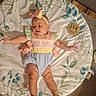 Nyla is registered to the contest to win money with this photo: baby, infant, child, portrait, lying_down, smiling, bow_headband, floral_blanket, milestone_photo, six_months, romper, pastel_clothing, outdoor_style, indoor, floor, carpet, wood_floor, arms_outstretched, hands, feet