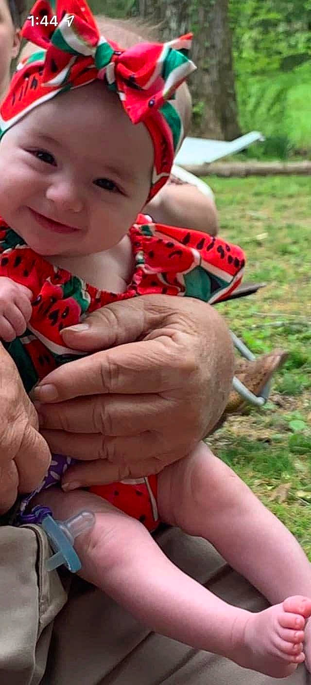Layla is registered to the contest to win money with this photo: baby_toddler_clothing, eye, face, finger, gesture, grass, hand, happy, head, headwear, joy, leaf, lip, mouth, nail, people_in_nature, person, photograph, red, skin