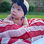 Annie is registered to the contest to win money with this photo: baby, infant, headband, blue_eyes, blanket, striped_blanket, outdoor, grass, fence, curious, portrait, closeup, child, person, summer, headwear, cute, young, skin, natural_light
