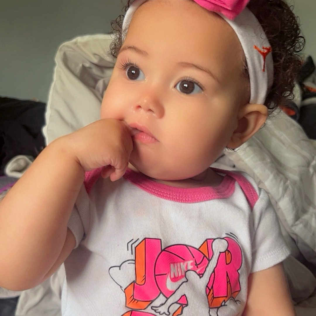 Xupiter joined the competition — help win amazing prizes! baby, blanket, child, clothing, curly_hair, cute, face, headband, indoors, infant, jordan, nike, onesie, person, pink_bow, portrait, sitting, skin, soft_lighting, thoughtful