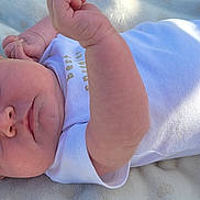 Evelyn joined the competition — help win amazing prizes! baby, infant, onesie, blanket, lying_down, face, skin, arm, soft, newborn, portrait, child, cute, indoors, peaceful, expression, head, human, resting, light