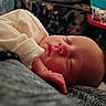 newborn, baby, infant, sleeping, portrait, face, closed_eyes, cream_clothing, onesie, blanket, cozy, indoors, resting, cuddled, peaceful, soft_lighting, closeup, human, family, home