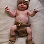 Charlie is registered to the contest to win money with this photo: baby, infant, crocheted_clothing, bear_hat, booties, diaper_cover, smile, lying_down, blanket, cute, cheeks, soft_texture, headwear, hand, footwear, skin, child, young, adorable, warm