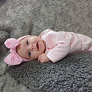 Khalayah is registered to the contest to win money with this photo: baby, infant, pink_bow, headband, smiling, lying_down, blanket, soft_texture, cute, child, portrait, happy, cozy, indoors, clothing, pink_outfit, face, small_hand, blue_eyes, toddler