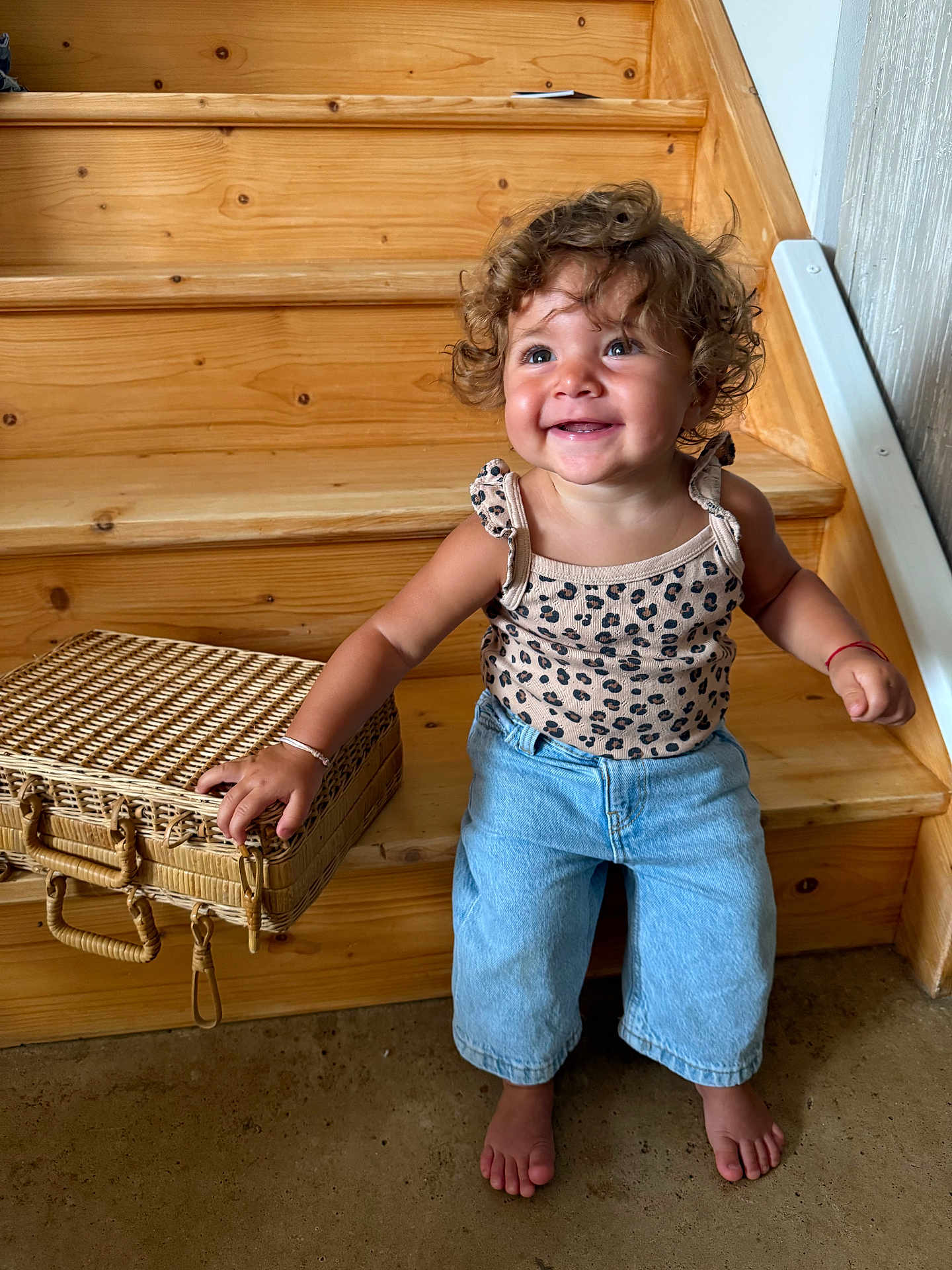 Cassie Anna June a rejoint le concours — aidez-le/la à gagner de superbes lots ! child, toddler, curly_hair, smiling, barefoot, wooden_stairs, basket, denim_pants, tank_top, indoor, happy, cute, person, portrait, casual_clothing, home, light_skin, sitting, natural_light, floor