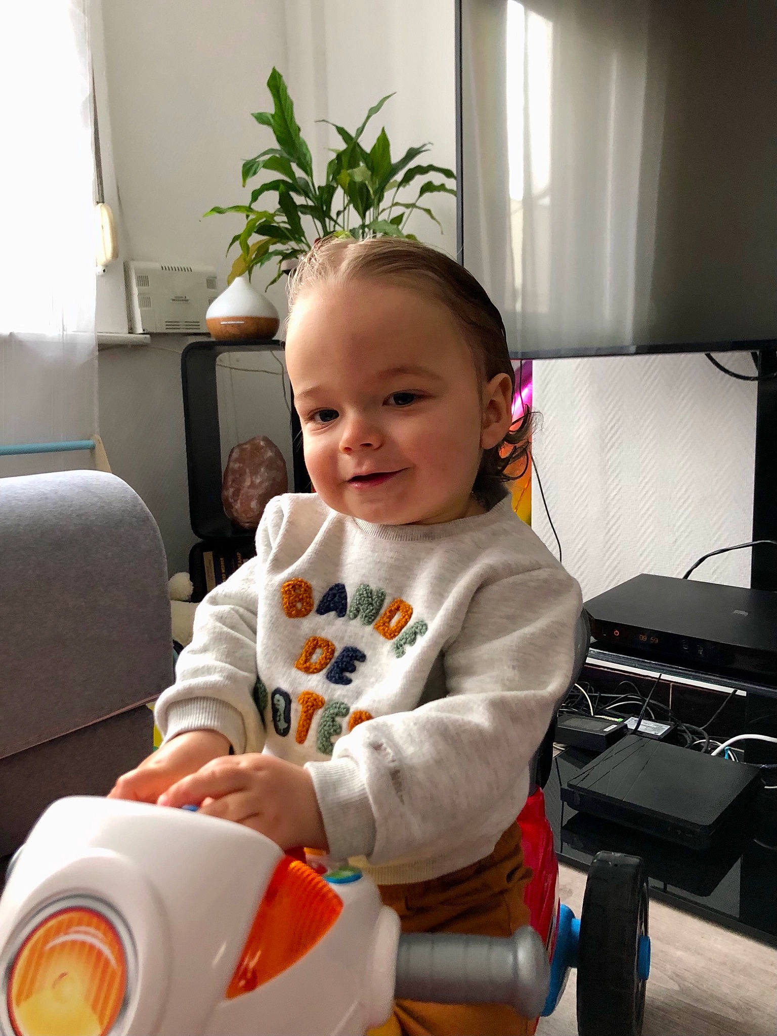 Orion participe au concours pour gagner de l'argent avec cette photo : baby, baby_toddler_clothing, child, comfort, computer_keyboard, flooring, flowerpot, fun, happy, home_appliance, houseplant, joy, office_equipment, office_supplies, peripheral, person, plant, room, sitting, smile