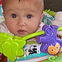 Alaeleea is registered to the contest to win money with this photo: baby, infant, face, eyes, toy, purple_monkey, green_leaf, yellow_flower, orange_surface, curious_expression, closeup, child, indoor, playtime, colorful, plastic_toys, head, person, baby_seat, cute