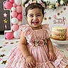 toddler, child, birthday, pink_dress, smiling, balloons, cake, celebration, party, happy, lace, flowers, hair_bows, indoors, decorations, festive, table, cute, person, portrait