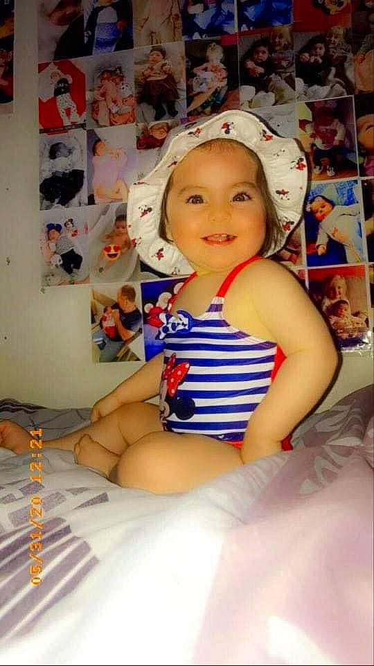 Julia participe au concours pour gagner de l'argent avec cette photo : abdomen, cap, carmine, child, event, fictional_character, finger, fun, glove, happy, hat, human_leg, joy, knee, leg, person, sitting, smile, t_shirt, thigh