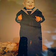 Bradley is registered to the contest to win money with this photo: baby, child, toddler, sailor_outfit, navy_uniform, portrait, smiling, happy, standing, indoor, vintage, warm_lighting, home, carpet, furniture, blurred_background, full_body, hands, navy_blue, nostalgic