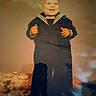baby, child, toddler, sailor_outfit, navy_uniform, portrait, smiling, happy, standing, indoor, vintage, warm_lighting, home, carpet, furniture, blurred_background, full_body, hands, navy_blue, nostalgic