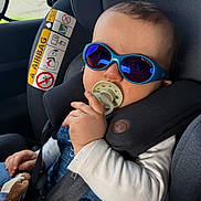 Ayden participe au concours pour gagner de l'argent avec cette photo : airbag_warning, baby, car_interior, car_seat, child, closeup, denim, hair, hand, infant, onesie, pacifier, plush_toy, portrait, reflection, safety_label, seatbelt, sunglasses, travel, window