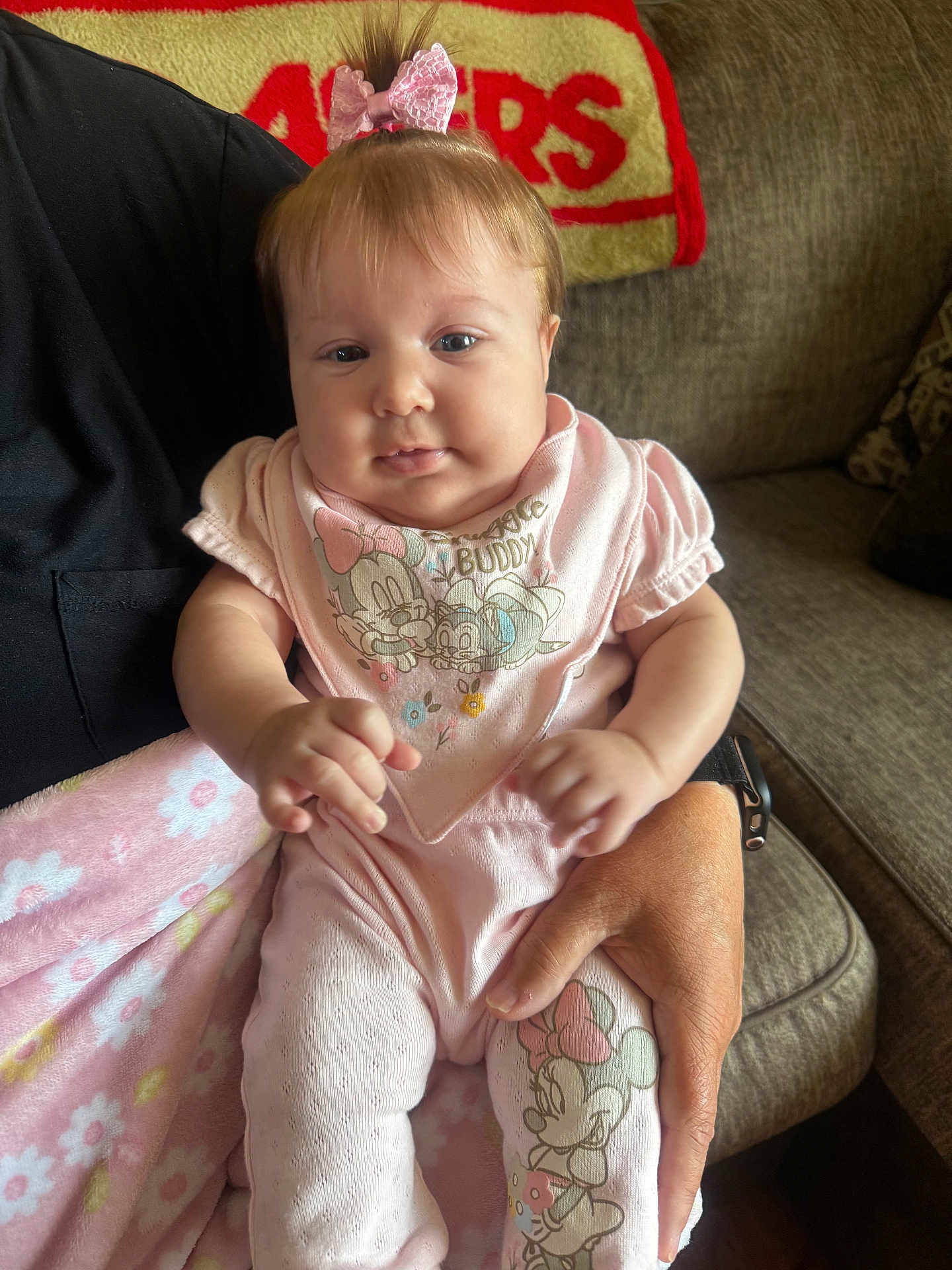 Oakley joined the competition — help win amazing prizes! baby, infant, pink_clothing, pajamas, bow, blanket, couch, person_holding_baby, hand, face, smiling, indoor, home, soft_toys, cartoon_character, minnie_mouse, cute, child, portrait, cozy