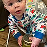 Hayes is registered to the contest to win money with this photo: baby, candid, child, colorful_clothing, curious, expression, face, floor, furniture, hand, highchair, holding, indoor, jar, pajamas, person, pickles, toddler, wooden_floor, young_child