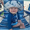 Hayes is registered to the contest to win money with this photo: barefoot, beach, beach_chair, blue_clothing, child, cute, happy, hat, ocean, outdoor, sand, sitting, smiling, striped_chair, summer, sunhat, sunny, toddler, vacation, whale_pattern