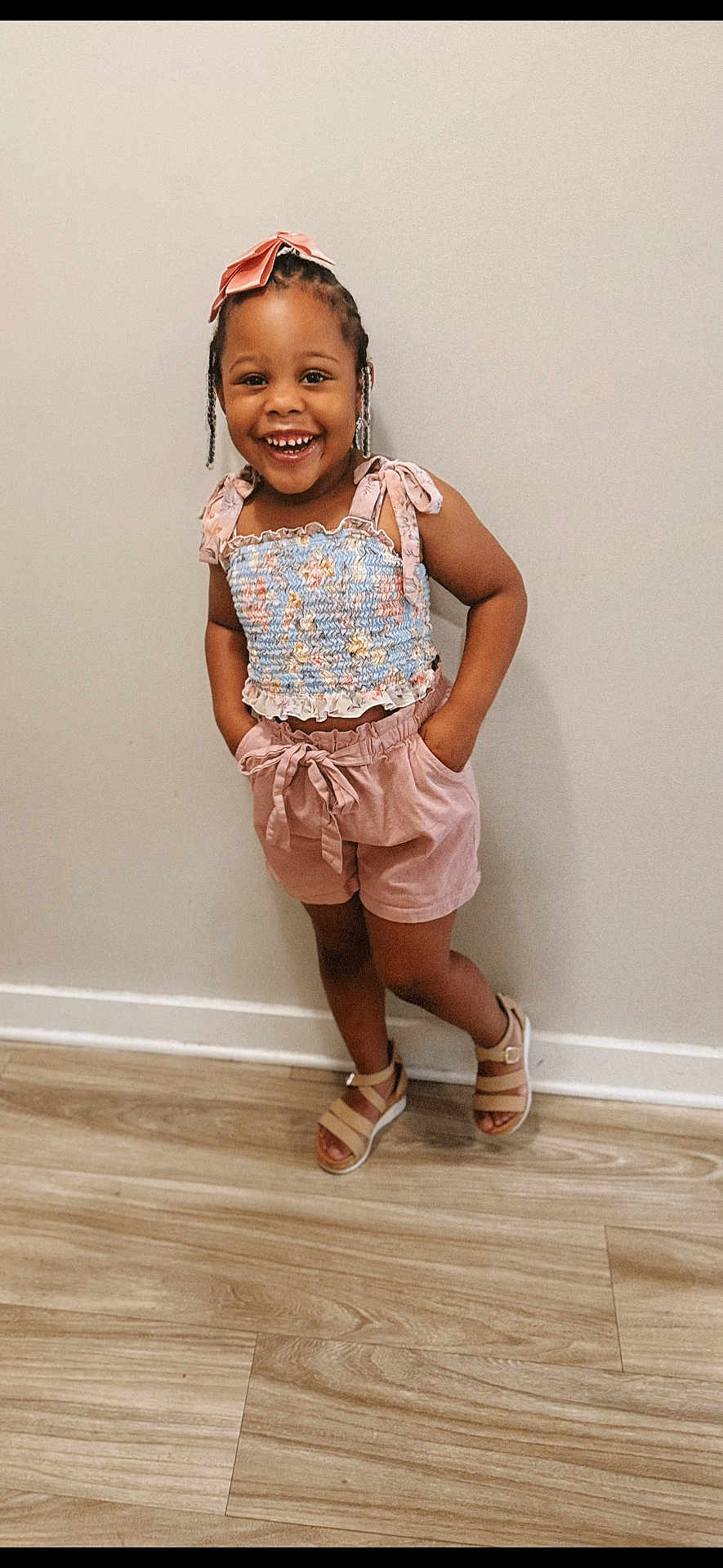 Alyssa Nevaeh is registered to the contest to win money with this photo: child, girl, smiling, standing, braids, bow, top, shorts, sandals, floor, wall, happy, cute, fashion, portrait, indoor, person, clothing, footwear, pose