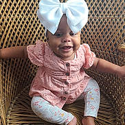 Alyssa Nevaeh joined the competition — help win amazing prizes! baby, child, smile, bow, headwear, dress, leggings, wicker_chair, furniture, happy, sitting, cute, indoor, infant, person, patterned_clothing, arm, foot, face, buttoned_dress