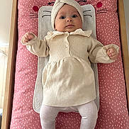 Mia participe au concours pour gagner de l'argent avec cette photo : baby, infant, child, changing_pad, pink, cream_clothing, headband, knitted, lying_down, cute, indoors, wooden_furniture, patterned_fabric, tights, small_hands, wide_eyes, portrait, soft_lighting, cozy, adorable