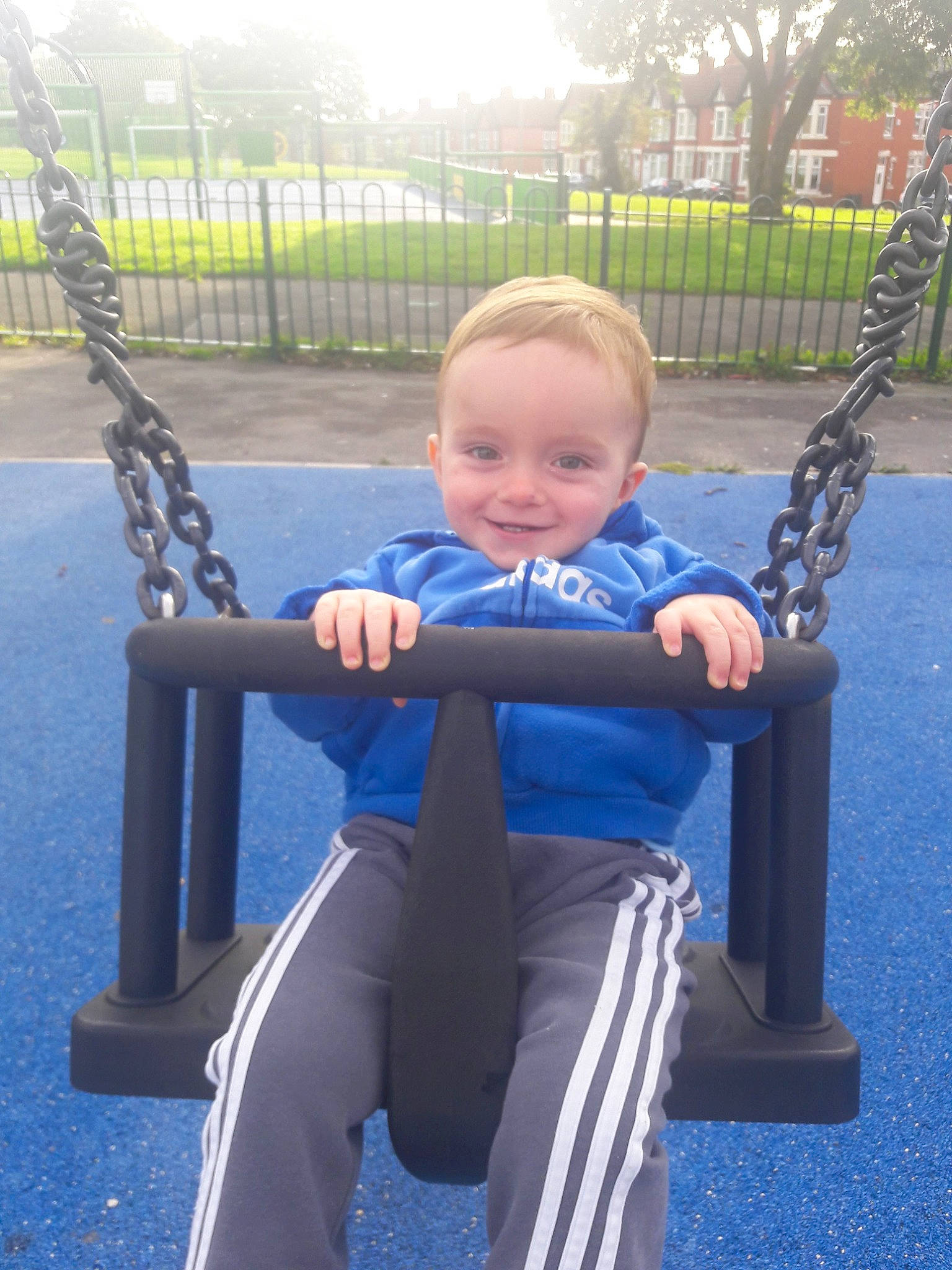 Layton James is registered to the contest to win money with this photo: baby, baby_toddler_clothing, blue, city, electric_blue, facial_expression, fence, fun, grass, joy, leg, leisure, people, person, plant, playground, recreation, smile, standing, swing