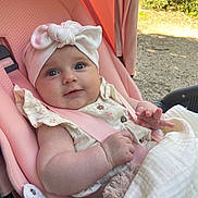 Aïna participe au concours pour gagner de l'argent avec cette photo : baby, blanket, bow, child, clothing, comfort, cute, happy, headband, infant, nature, outdoor, person, pink, seatbelt, smile, soft, stroller, sunlight, toy