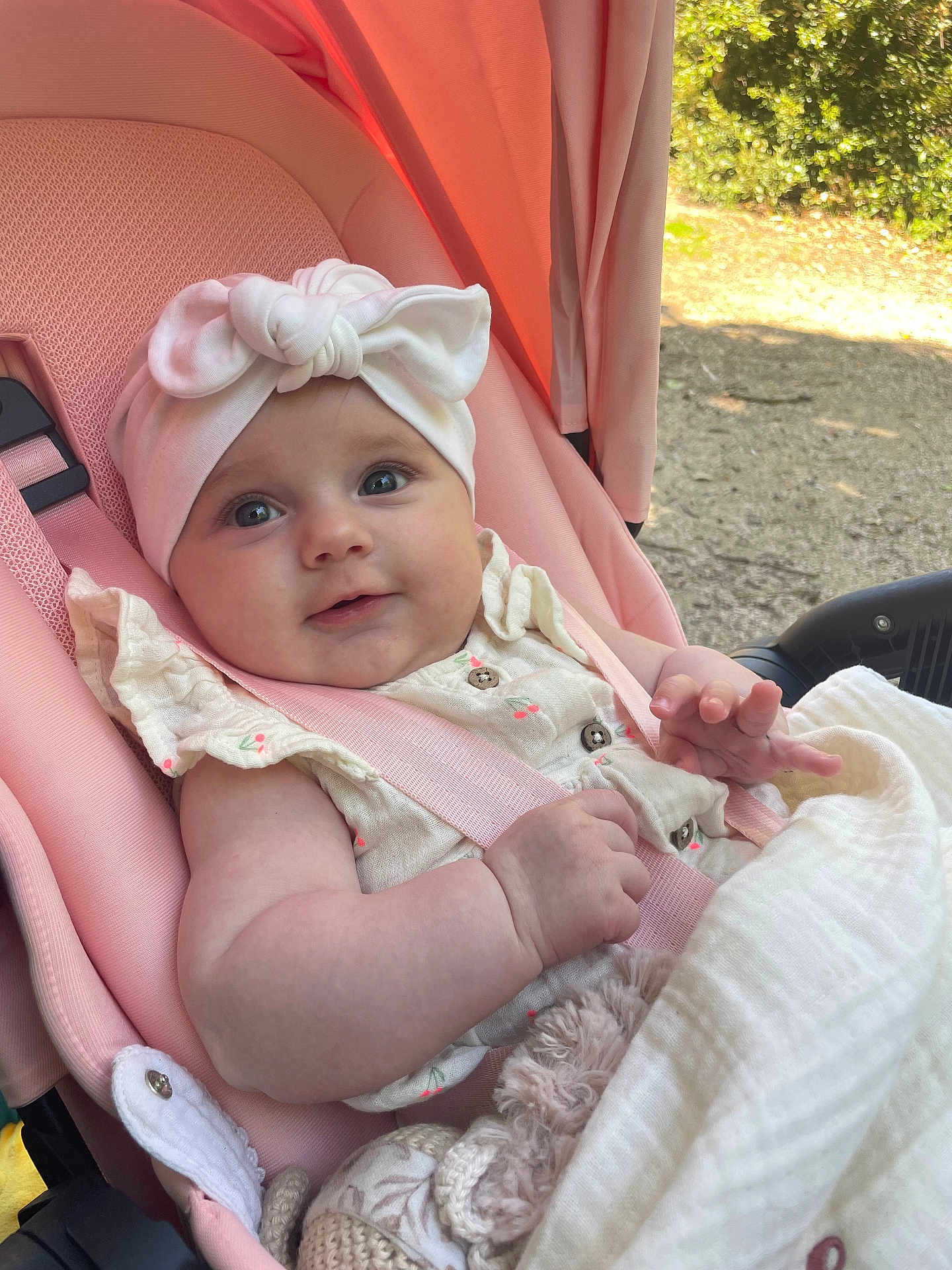 Aïna participe au concours pour gagner de l'argent avec cette photo : baby, blanket, bow, child, clothing, comfort, cute, happy, headband, infant, nature, outdoor, person, pink, seatbelt, smile, soft, stroller, sunlight, toy