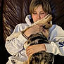 person, dog, couch, white_hoodie, brown_leather, indoor, pet, cuddle, affection, paw, casual_clothing, short_hair, relaxation, friendly, animal, comfort, playful, close_up, home, leisure