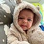 baby, child, hoodie, fluffy_clothing, cute, face, expression, indoor, pillow, cloud_pattern, infant, person, warm_clothing, zipper, plush, soft_texture, closeup, portrait, blue_eyes, cozy