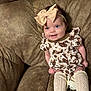 Wrenleigh is registered to the contest to win money with this photo: baby, infant, smile, headband, bow, couch, plush, brown, clothing, pattern, cowboy_boots_pattern, socks, kneehighs, happy, portrait, indoors, cute, child, person, relaxing