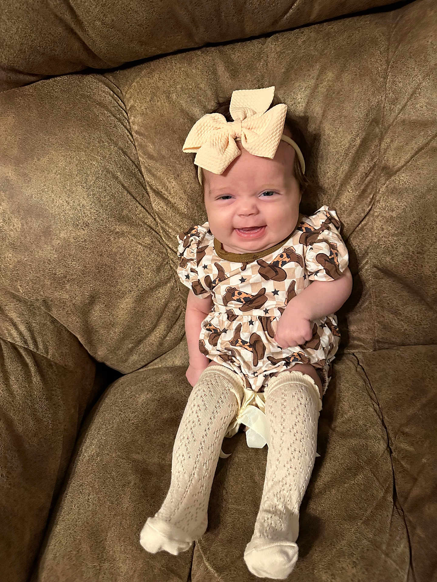 Wrenleigh joined the competition — help win amazing prizes! baby, child, smile, headband, bow, dress, patterned_clothing, sitting, couch, furniture, happy, indoor, young_child, cute, knit_socks, infant, person, small_person, cozy, comfort