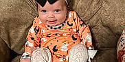 Wrenleigh is registered to the contest to win money with this photo: baby, child, smiling, bow, headband, orange_outfit, halloween_theme, ghost_print, pumpkin_print, white_tights, knit, couch, brown_couch, indoor, person, infant, cute, happy, sitting, cozy