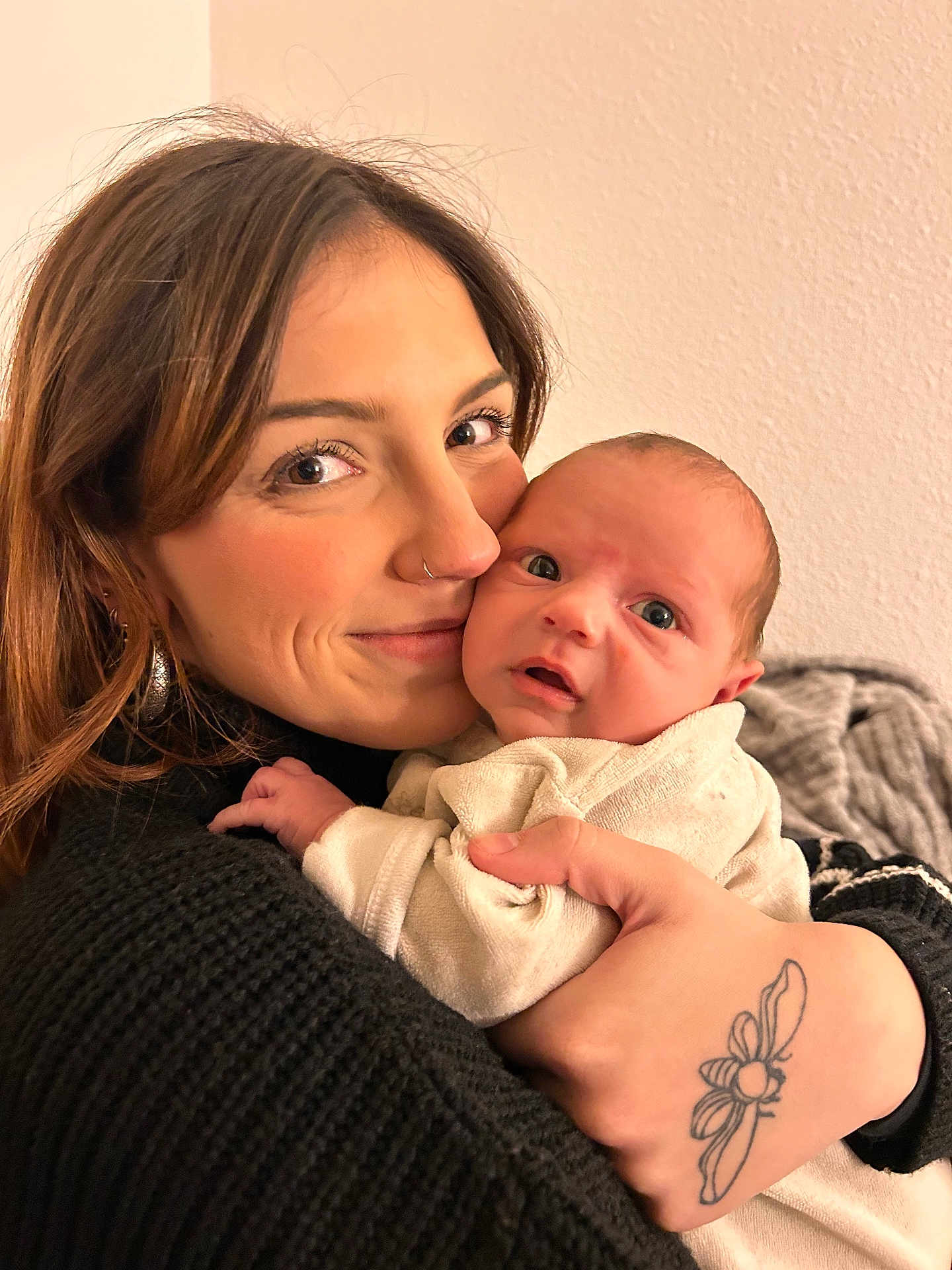 Luciano Ange Milo participe au concours pour gagner de l'argent avec cette photo : baby, black_sweater, clothing, cozy, curious, expression, face, flower_tattoo, holding, hug, indoor, intimate, newborn, nose_ring, person, portrait, skin, tattoo, warmth, woman