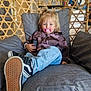 child, pacifier, chair, cushion, jeans, jacket, sneakers, indoor, hand, wood, furniture, relaxing, blue_eyes, blonde_hair, casual_clothing, device, comfort, home, portrait, seated