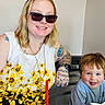 blond_hair, blue_shirt, casual, child, drink, family, food, friendship, happy, indoor, person, relaxed, restaurant, short_hair, smile, sunglasses, table, tattoos, together, woman