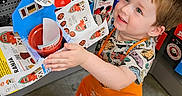 Dean joined the competition — help win amazing prizes! apron, boy, child, clothing, colorful, craft, floor, gift_cards, happy, holding, indoor, playful, project, retail, shoes, short_hair, smiling, store, toddler, young