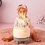 baby, child, cake, birthday, pink, headband, dress, frosting, messy, smiling, sitting, spatula, celebration, floor, rug, decorations, flowers, cute, indoors, portrait