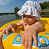 beach, child, clouds, family, fingers, hand, inflatable_ring, lake, outdoors, playing, portrait, shoreline, sky, smile, sun_hat, sunny, toddler, vacation, water, yellow_float