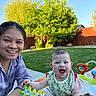 woman, baby, smile, outdoor, grass, walker, toy, greenery, fence, sunlight, happy, child, person, nature, playtime, face, casual, daytime, family, portrait